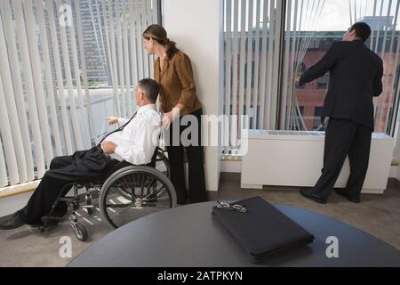 Three business executives looking through windows in an office Stock Photo