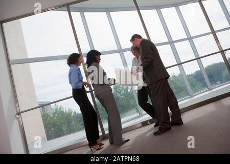 Team of business people standing and looking over documents Stock Photo