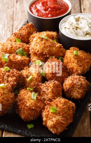 Coconut breaded chicken nuggets served with ketchup and mayonnaise close-up on a slate board on a table. Vertical Stock Photo