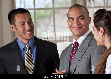 Portrait of three young professionals standing and talking Stock Photo