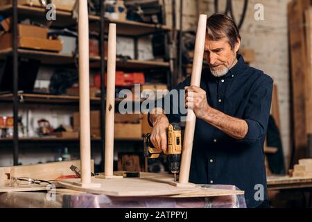 Senior carpenter repairing a table in his workshop Stock Photo