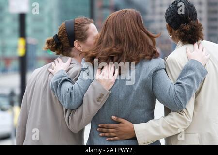 Rear view of three women standing together. Stock Photo