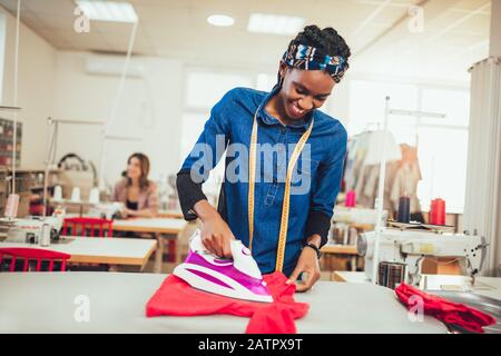 Tailor ironing in the modern sewing workshop. Stock Photo