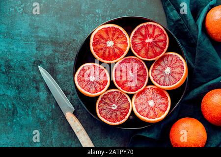 Cutted blood oranges in a plate on a dark blue background. Top view, copy space. Stock Photo