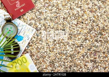 Travel concept, tourism. Compass, map, passport, fern, lie on the sea sand. Stock Photo