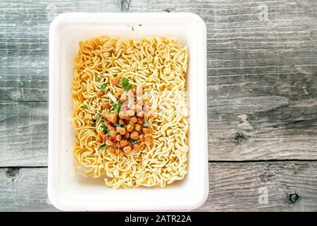 bowl of ramen soup. Tom Yam kun instant noodles with dried meat and vegetable additives on a wooden table. Hot brewed quick soup in a disposable packa Stock Photo