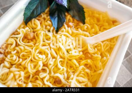 bowl of ramen soup. Tom Yam kun instant noodles with dried meat and vegetable additives on a wooden table. Hot brewed quick soup in a disposable packa Stock Photo