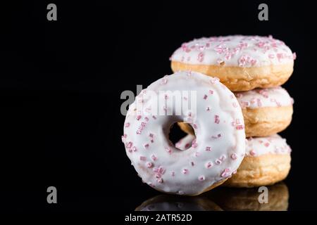 Stack of  White Chocolate Donuts or Doughnuts on Black Background with Copy Space. Stock Photo