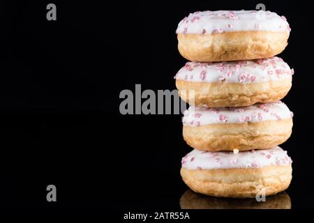 White Chocolate Donuts or Doughnuts Tower on Dark Background . Stock Photo