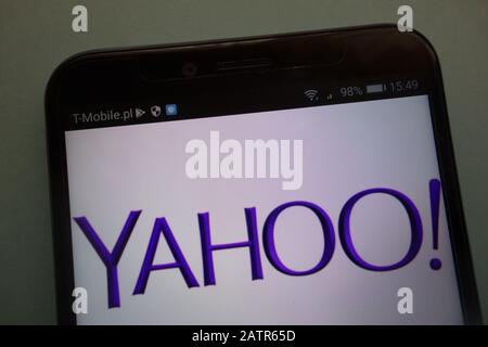 Yahoo logo on phone screen set against blue background with earbuds and ...