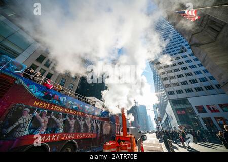 Steam rises and drifts over the Double decker bus on the Fifth Avenue among the Midtown Manhattan buildings in New York City NY USA on Dec. 22 2019. Stock Photo