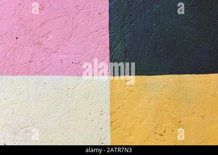 Texture of a multi-colored wall close-up. The wall is painted in green, pink, yellow and stone, divided into segments Stock Photo