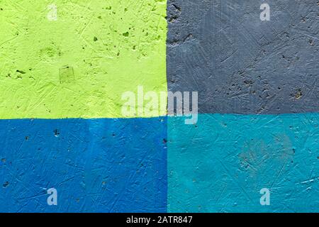 Texture of a multi-colored wall close-up. The wall is painted in blue, green, grey, turquoise divided into segments. Stock Photo