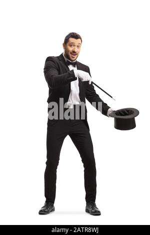 Full length shot of a magician making a magic trick with a wand and a tophat and looking at the camera isolated on white background Stock Photo