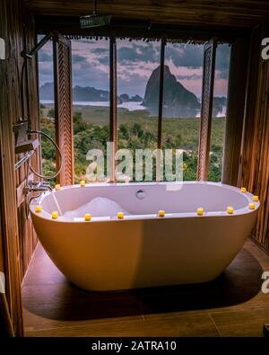 Luxury bathroom looking out over the ocean of Phangnga Bay Thailand, bath tub in wooden room Stock Photo