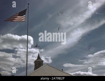 American flag flying over roof of a building with cupola top in bright sunlight, likely in New England, United States, 1965. () Stock Photo