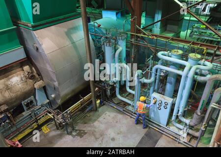 Worker wearing hard hat and reflective vest using equipment with gauges and monitors Stock Photo