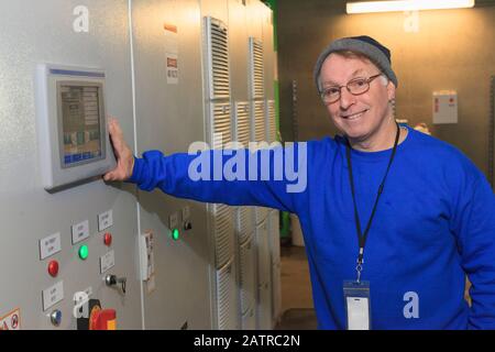 Man at digital screen in the workplace with indicator lights on a wall Stock Photo