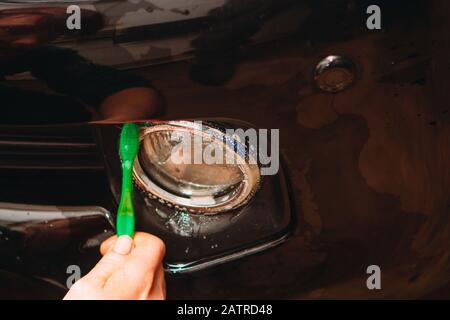 An employee of the car wash thoroughly washes conducts detaling and applies protective equipment to the body of an expensive car Stock Photo