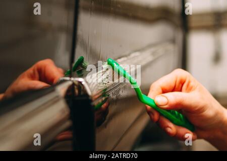 An employee of the car wash thoroughly washes conducts detaling and applies protective equipment to the body of an expensive car Stock Photo