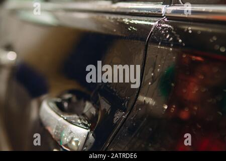 An employee of the car wash thoroughly washes conducts detaling and applies protective equipment to the body of an expensive car Stock Photo