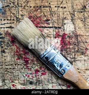 Square photo of an one inch brush on wooden workbench stained grunge textured surface. Stock Photo