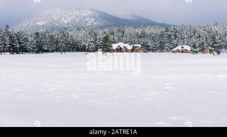 Large home on a meadow covered in snow in Flagstaff, Arizona, with the forest and mountain in the background. Stock Photo