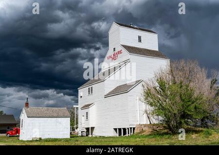 White grain elevator in Val Marie under dramatic storm clouds; Val Marie, Saskatchewan, Canada Stock Photo