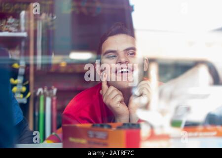 Middle Eastern man with Down Syndrome smiling at work Stock Photo