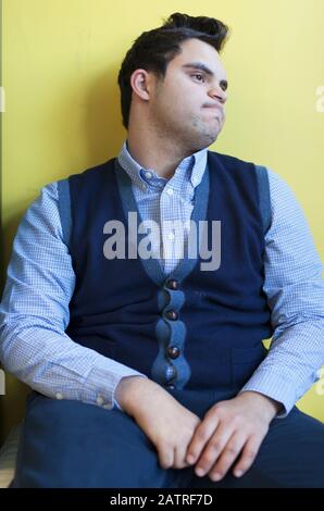 Middle Eastern man with Down Syndrome sitting against wall Stock Photo