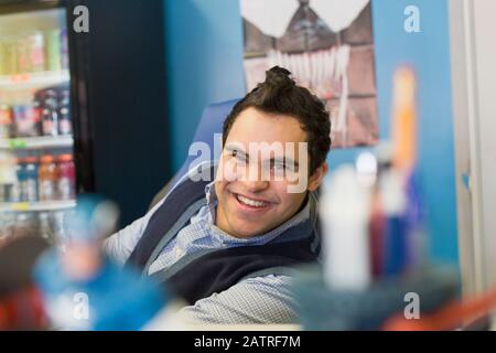 Middle Eastern man with Down Syndrome smiling at work Stock Photo