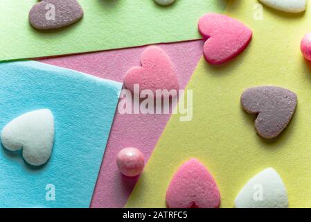 Tri-color sugar hearts on a pink background closeup. Sugar hearts on pink paper in three colors. Stock Photo