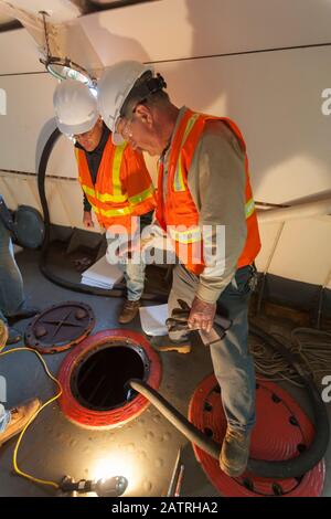 Environmental cleanup engineers in hold of ship cleaning hazardous materials Stock Photo