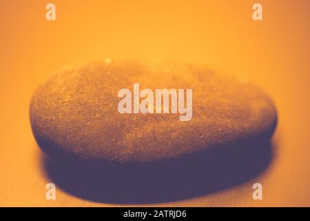 One big pebble stone on the table, orange light Stock Photo