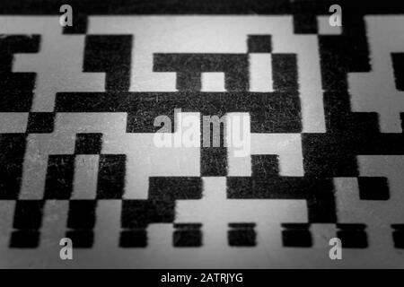Abstract monochrome close up of isolated printed QR data matrix bar code on white paper label background from material inventory tracking system Stock Photo