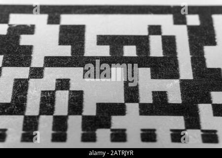 Abstract monochrome close up of isolated printed QR data matrix bar code on white paper label background from material inventory tracking system Stock Photo