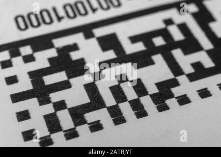 Abstract monochrome close up of isolated printed QR data matrix bar code on white paper label background from material inventory tracking system Stock Photo