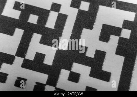 Abstract monochrome close up of isolated printed QR data matrix bar code on white paper label background from material inventory tracking system Stock Photo