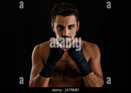 Muscular boxing man ready to fight on black background Stock Photo