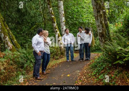 Family walking and talking on a trail in a park with forest; Langley, British Columbia, Canada Stock Photo