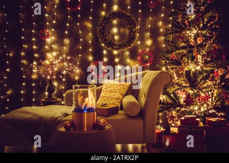 Selective focus on modern freestanding portable glass and copper metal fireplace burning bio ethanol gas on living room table with cozy Christmas eve Stock Photo