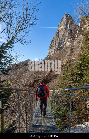 Hiker while crossing a Tibetan bridge located along a path on the - Small Dolomites - in Italy Stock Photo