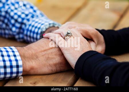 A mature couple praying together at a picnic table after spending some quality time discussing their faith; St. Albert, Alberta, Canada Stock Photo