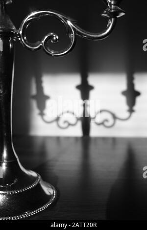 Closeup candlestick on three candles with shadow reflection on the wall. Stock Photo