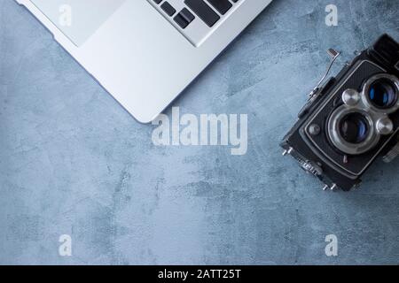 Old medium format camera of black color next to current laptop, on light gray background Stock Photo