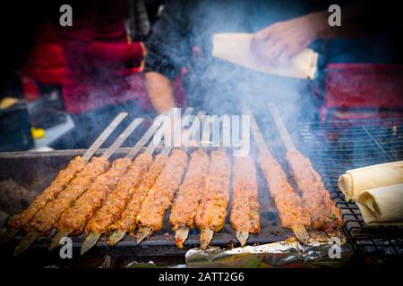 Kebab or kebap on metal skewer barbecue and embers in the kebab restaurant. Skewering bbq Kebab. Traditional Turkish Adana Kebab with lavas Stock Photo