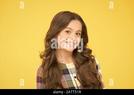 Perfect curly hairstyle. Different shaped curling wands do to your hair. From tightly defined ringlets to loose beachy waves. Curve soft curl tong. Curly and happy. Small smiling child curly hairdo. Stock Photo