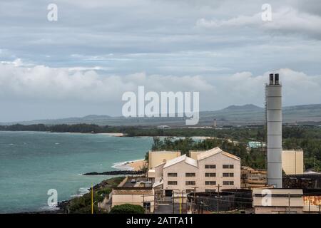 Kahului, Maui,, Hawaii, USA. - January 13, 2020: Old defunt sugarcane processing plant in harbor area bordering the azure ocean, under cloudscape with Stock Photo