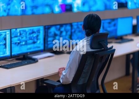 Group of Security data center operators (administrators) working in a group at a CCTV monitoring room while looking at multiple monitors ( computer sc Stock Photo