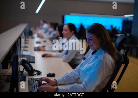 Group of Security data center operators (administrators) working in a group at a CCTV monitoring room while looking at multiple monitors ( computer sc Stock Photo